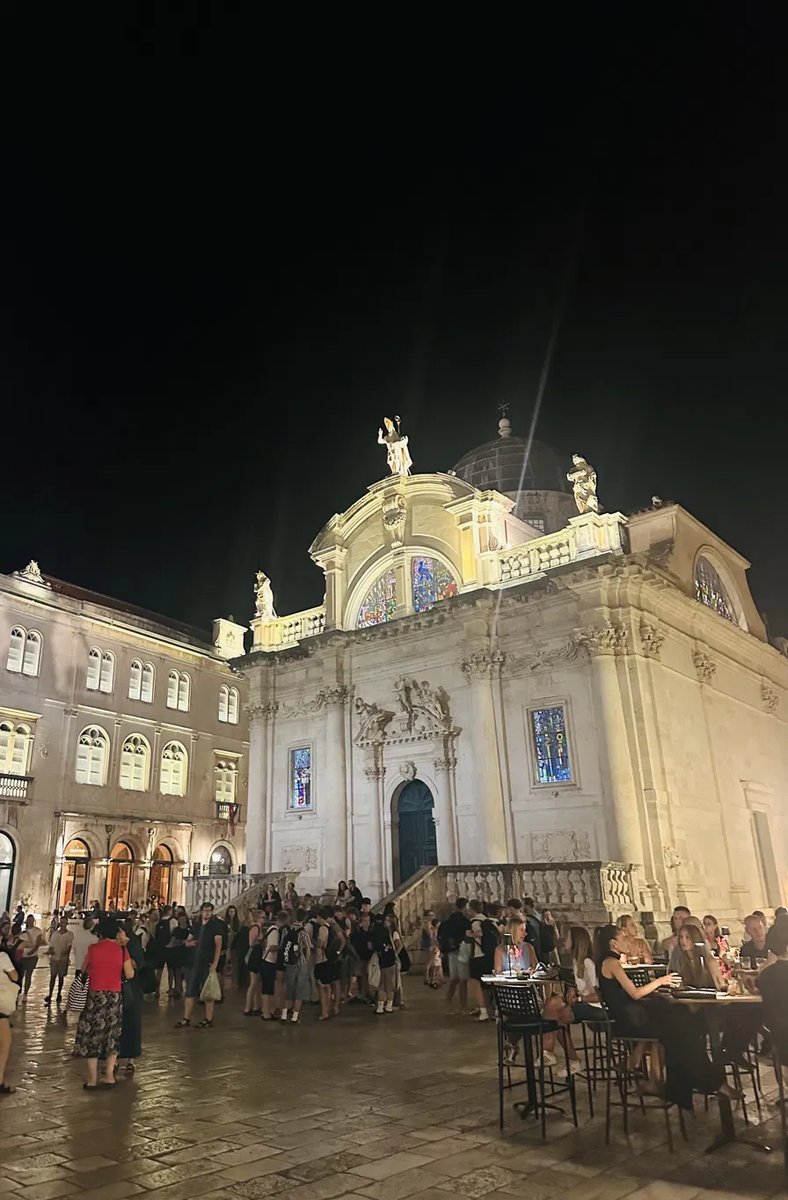 St. Blaise's church lit up at night with crowds