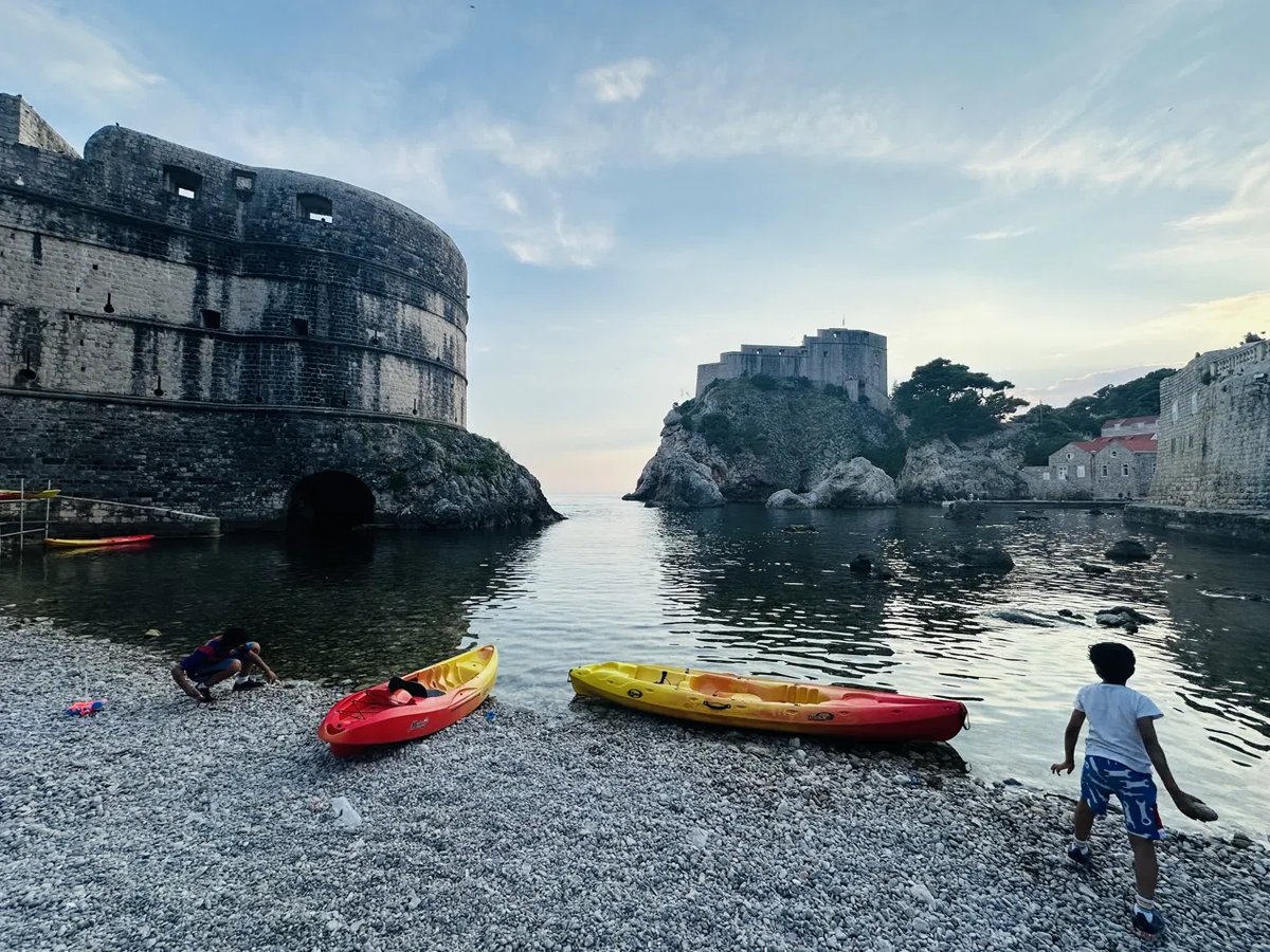 Kayaks pulled up on a pebble beach below the walls
