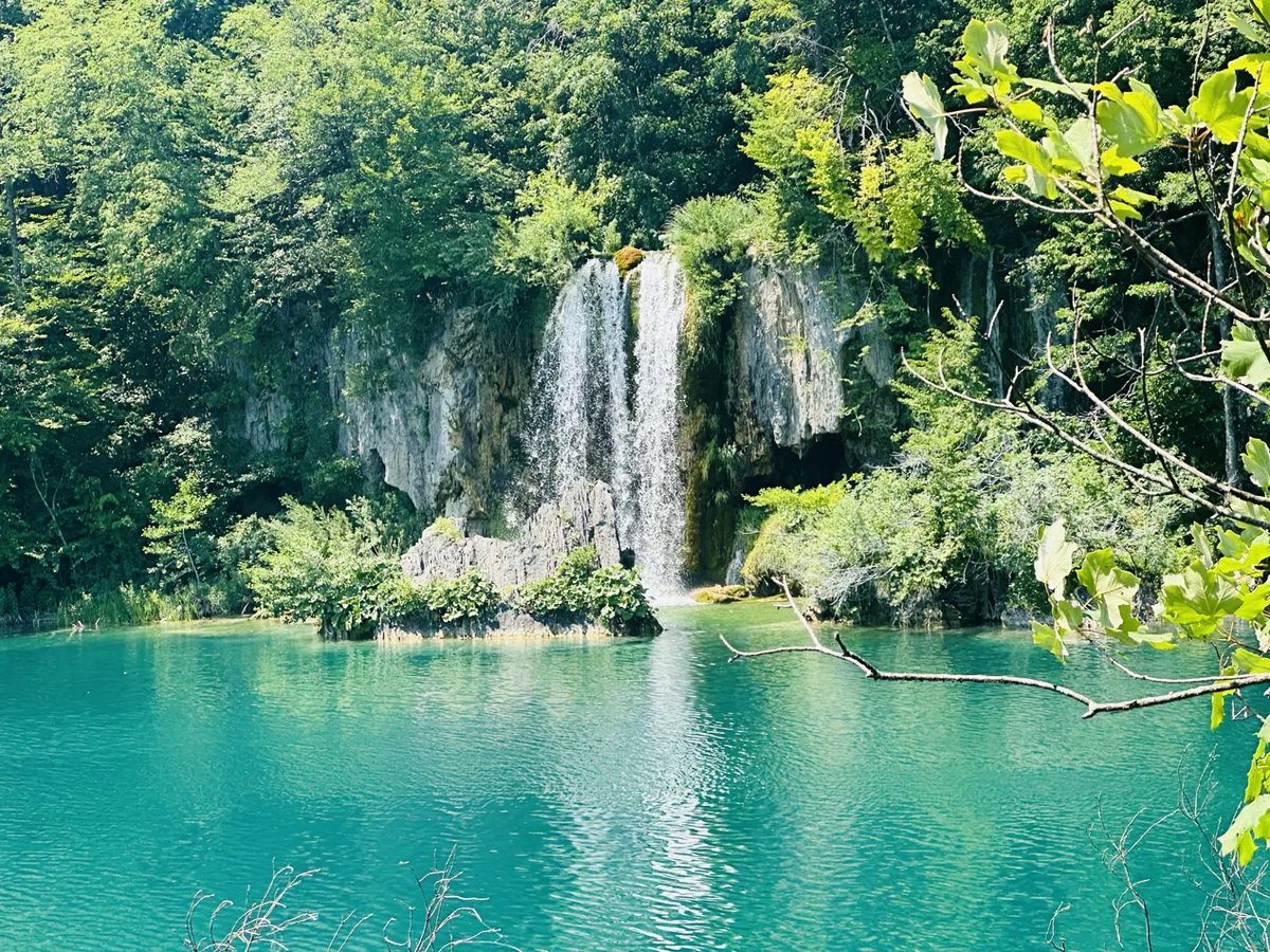 Waterfall cascading into a turquoise lake at Plitvice