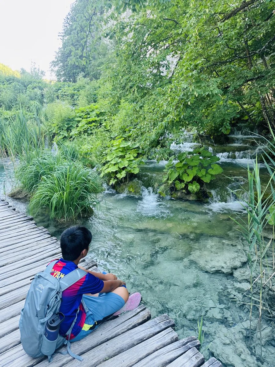 Kid sitting quietly at the water's edge watching the stream