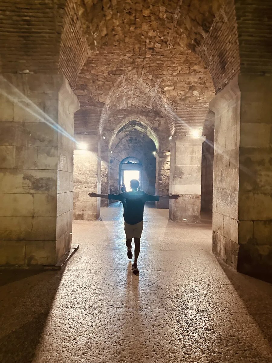 Standing arms outstretched in the Diocletian's Palace substructures corridor
