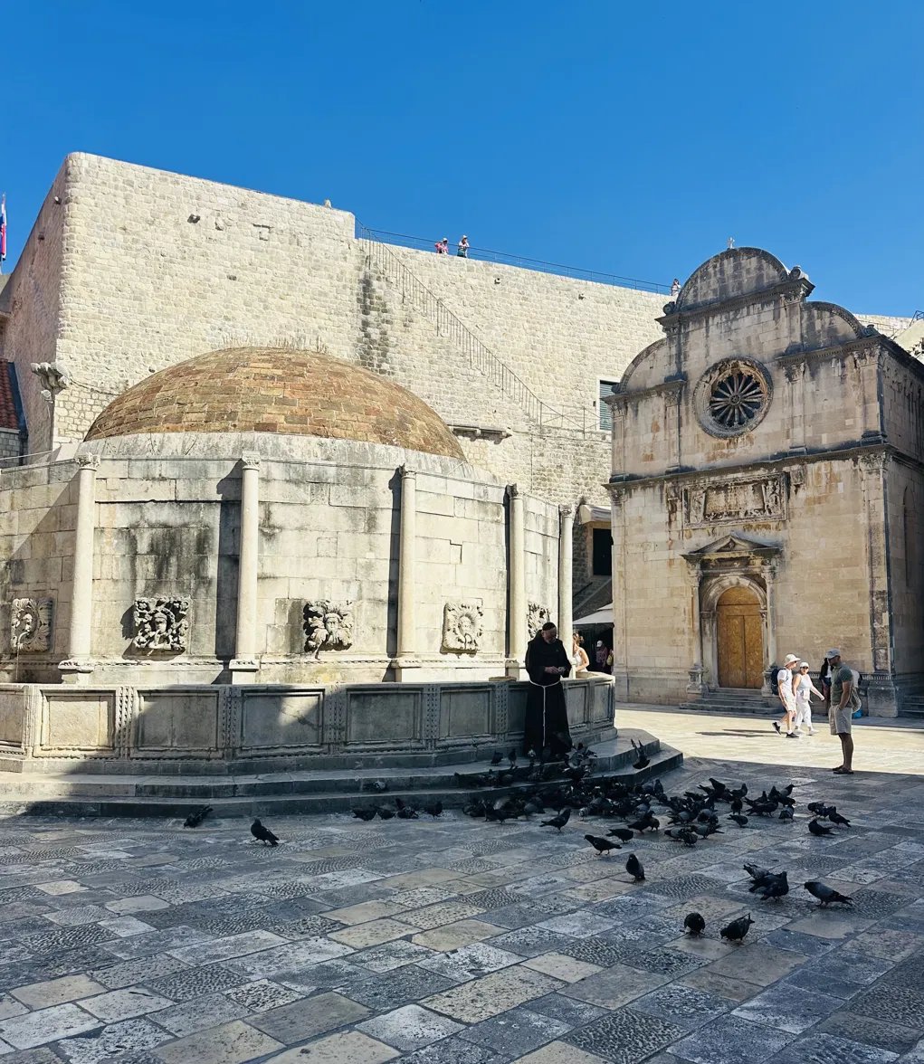 A priest feeding pigeons in Dubrovnik's cathedral square